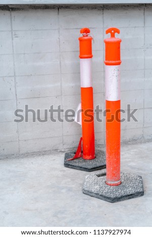 Two orange plastic poles with white strip lines for traffic on concrete road