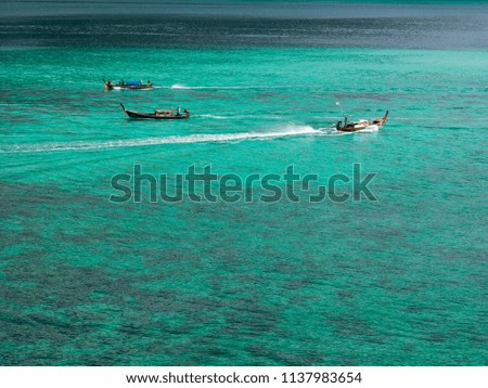 Three wooden long tail boats in turquoise water sea in sunny summer day for vacations holiday concept.