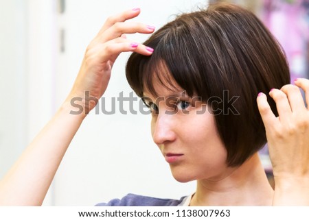 Beautiful young woman is worried about her first grey hair. Royalty-Free Stock Photo #1138007963