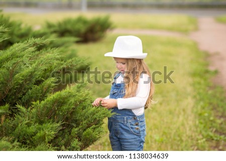 little girl blonde in jeans overalls walking in city park. A healthy time for children
