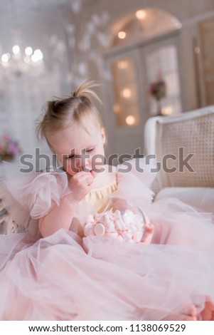 Charming little girl dressed like a ballerina poses in a bright room with shiny lamps