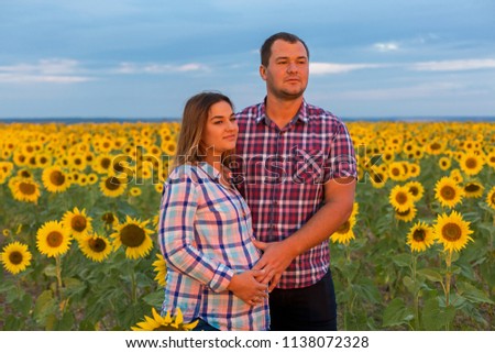 Young couple in a field of sunflowers, pregnant girl in sunflowers