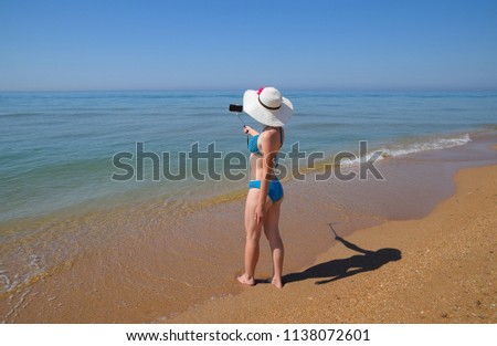 A girl with a selfie stick on the beach. Selfie on the beach.