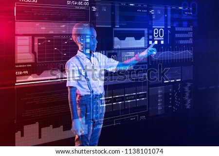 Cute boy. Calm attentive child smiling and feeling glad while touching the icon on a transparent screen and using his new modern computer