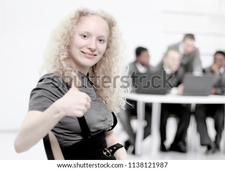 young female assistant showing thumb up standing in the office