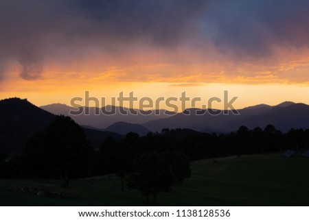 Sunset over the Colorado Mountains with Dark Trees and Grass in Foreground