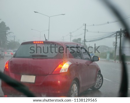 A car with its signal light on carefully making a U-turn in a heavy rain on a rainy day - driver's perspective from another car behind  Royalty-Free Stock Photo #1138129565