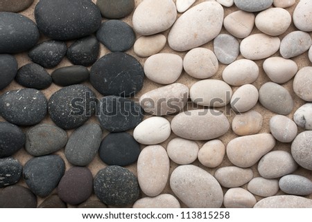 Black and white stones lie side by side on the sand