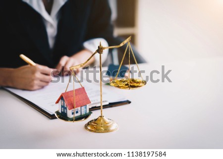 Money coin with wooden house on gold brass balance scale. Saving money for real estate with buying a new home and loan for prepare in the future concept. Royalty-Free Stock Photo #1138197584