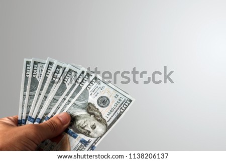 US dollars in a male hand on a light background. Concept Bribe, additional work, salary, bonus, bonus, cache back.