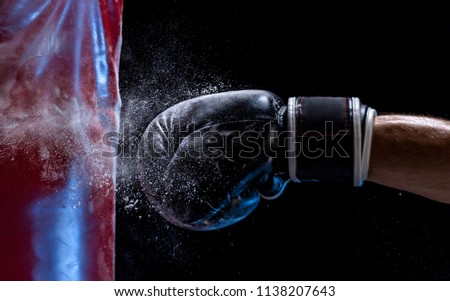 Close-up hand of boxer at the moment of impact on punching bag over black background Royalty-Free Stock Photo #1138207643