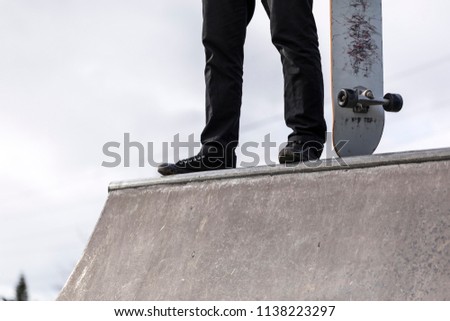 Skateboarder at Skatepark. A mature male skater standing on the edge of a skatepark between runs 