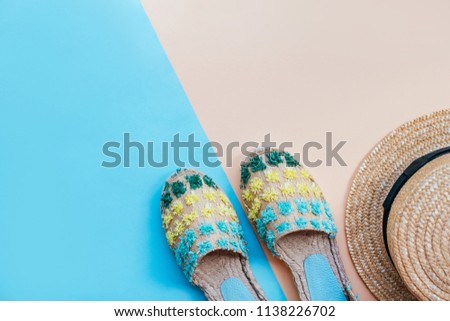 Summer fashion flatlay with straw hat and espadrille sandals on the two-toned blue and beige background. Perfect beach set for holidays on the sea. Marina style.