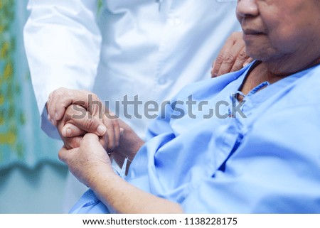Doctor holding touching hands Asian senior or elderly old lady woman patient with love, care, helping, encourage and empathy at nursing hospital ward : healthy strong medical concept 
