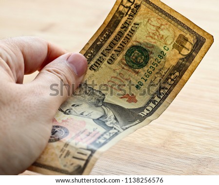A Caucasian hand holding a USA ten dollar note.  This image can be used to represent money or payment. This image has selective focusing. 