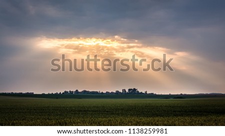 Dark sky with clouds during  sunrise. The rays of the sun break through a dark cloud