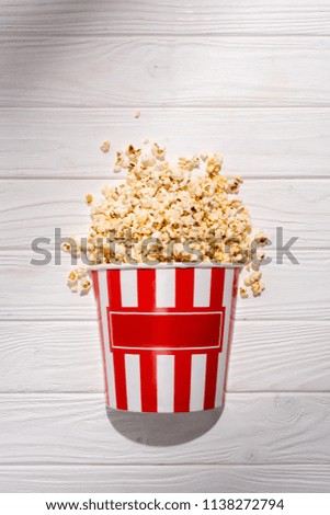 flat lay with disposable bucket with popcorn on white wooden surface