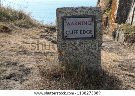 a stone warning sign on a cliff edge at Gurnard's Head, Cornwall, England