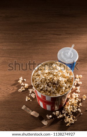 close up view of paper bucket with popcorn, soda drink and retro cinema tickets on wooden tabletop