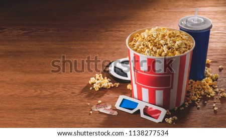 close up view of paper bucket with popcorn, soda drink, 3d glasses on wooden tabletop