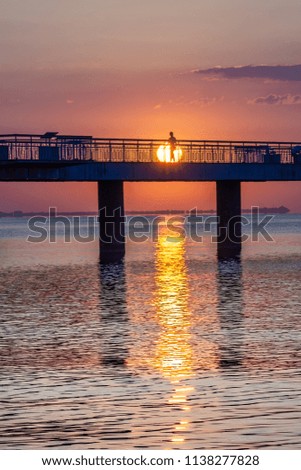 Beautiful sunrise at the sea. Girl walking on the bridge in the morning. 