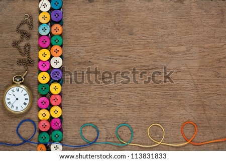 Pocket watch, colorful buttons, thread on oak wooden textured background