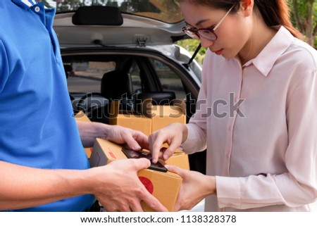Woman signing receipt on mobile phone from delivery man to get her package, delivery concept