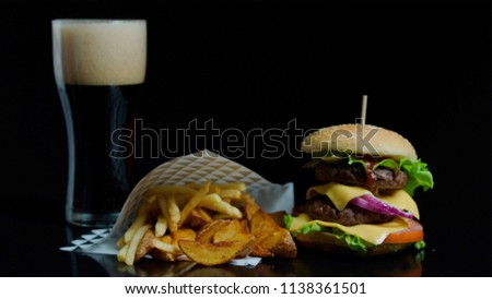 Pouring glass with coca-cola and tasty burger, french fries on the black background for commercial