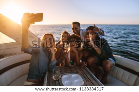 Cheerful young people posing for a selfie at boat party. Crazy friends enjoying a party on private yacht and taking selfie.