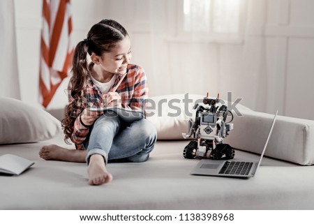 Robot as a model. Talented beautiful little girl picturing her toy  watching cartoon while spending her leisure 