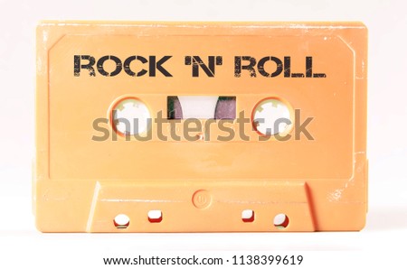 A vintage cassette tape from the 1980s era (obsolete music technology) with the text Rock 'n' roll (not in the original image, my addition). Color: cream, salmon. White background.
