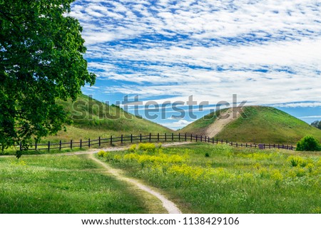 Royal Mounds - large barrows located in Gamla Uppsala village, Uppland, Sweden (70 km from Stockholm).  Beautiful Viking graves covered by grass. Gamla Uppsala is area rich in archaeological remains. Royalty-Free Stock Photo #1138429106