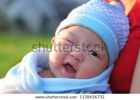 Little cute baby happy smiling baby boy sitting in field on fresh green grass sunny day, horizontal picture