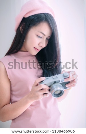 Asian woman holding and looking display of camera.