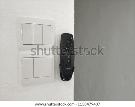 black fan remote control and white switch on wall