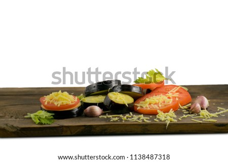 Summer food: sliced eggplant and tomato. Tomatoes, aubergines, cheeses, garlic and celery on a wooden board.