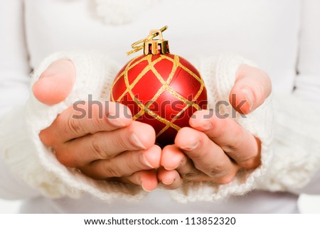 Woman's hand holding a Christmas ball on a white background.