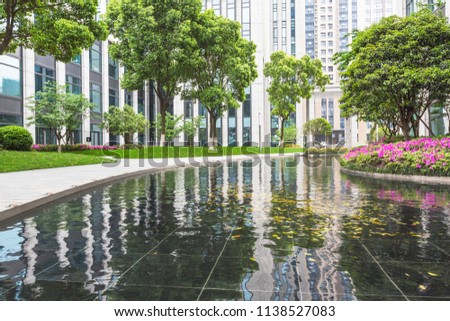 A modern business district park green landscape reflected in water.