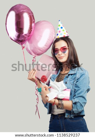 Young happy woman with pink gift box and balloons. Birthday holiday background