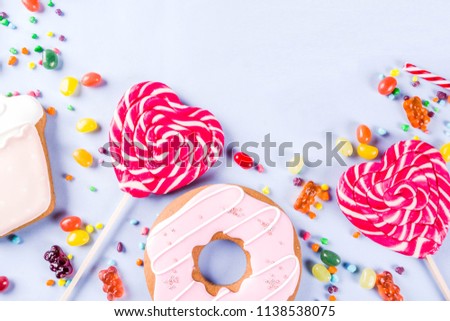 Sweets creative lay out, dessert concept with lollipops, jellies, candy, cookies donuts and cupcakes, light blue background top view copy space