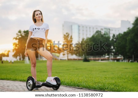 Young attractive woman with hoverboard outdoors in the park at the sunset. Toned