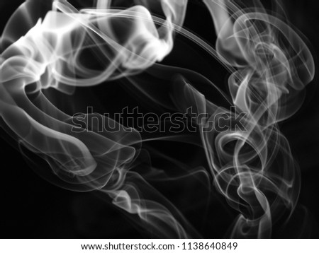 A close-up, black and grey photograph of a thick waft of smoke drifting over a black background. Smoke texture/overlay.