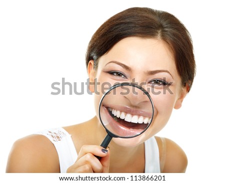 funny woman smiling and show teeth through a magnifying glass over white background