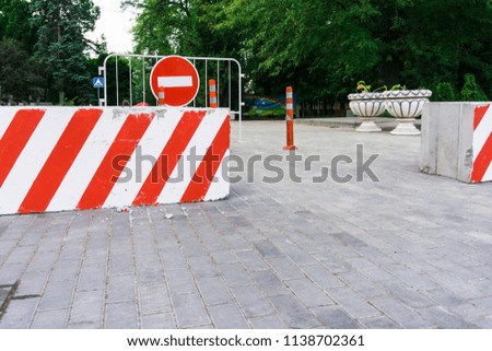Blocked passage through the central streets in the city center with the help of concrete blocks with beautiful stripes, metal bars, prohibiting signs and columns
