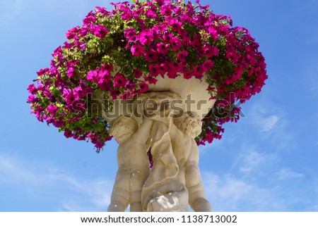Beautiful view with figure fragment of Luxembourg Garden in Paris City, France. Purple flowers on big sculpture pot. The Luxembourg Palace in the summer at sunny day.