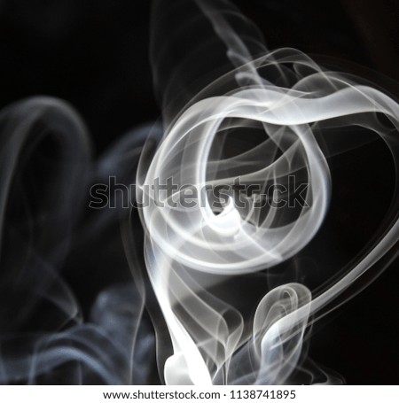 A thick waft of smoke drifting over a black background. Smoke texture/overlay.