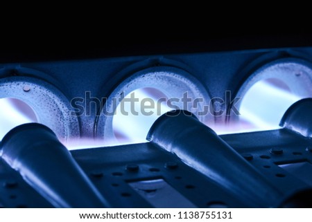 Closeup Shot Of Home Furnace Burner Ignited With Crimson Blue Flame Royalty-Free Stock Photo #1138755131