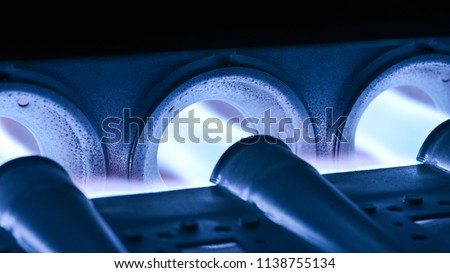 Closeup Shot Of Home Furnace Burner Ignited With Crimson Blue Flame Royalty-Free Stock Photo #1138755134