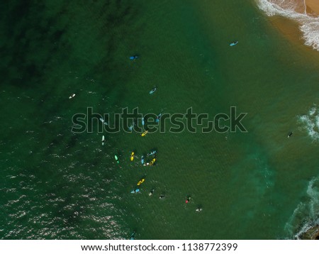 Aerial view of surfers in the ocean on a summer day. Surf Spot on the Portuguese coastline. Drone shot.