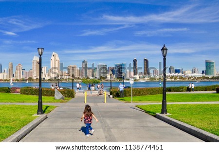 Little girl running in a hot summer day with buildings in the horizon